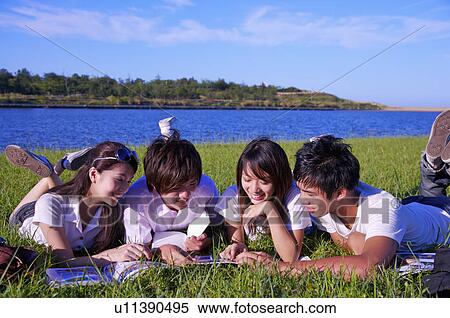 Four people lying on the lawn and reading book together, View Large Photo Image Stock Photography - Four people lying on the lawn and reading book together,. Fotosearch