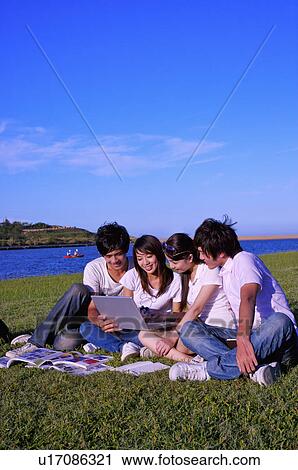 Four people sitting on the lawn and looking at the laptop together, View Large Photo Image Stock Image - Four people sitting on the lawn and looking at the laptop together,. Fotosearch
