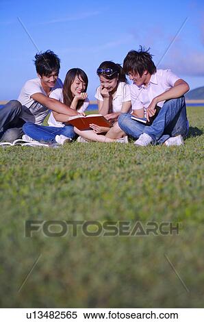 Four people sitting on the lawn and reading a book together, View Large Photo Image Stock Photography - Four people sitting on the lawn and reading a book together,. Fotosearch