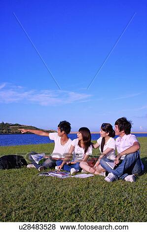 Four people sitting on the lawn, pointing and looking away, View Large Photo Image Stock Photo - Four people sitting on the lawn, pointing and looking away,. Fotosearch
