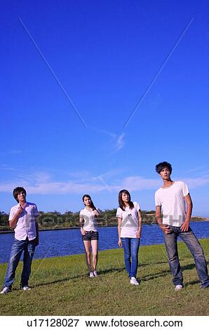 Four people standing on the lawn together and looking away, View Large Photo Image Stock Photo - Four people standing on the lawn together and looking away,. Fotosearch
