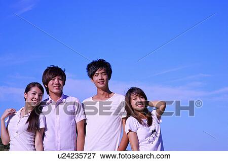 Stock Photo - Four people standing together with arms around and looking away with smile,. Fotosearch