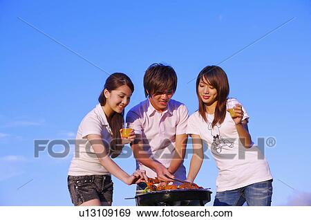 Three people barbecuing outside and holding drink, View Large Photo Image Stock Photo - Three people barbecuing outside and holding drink,. Fotosearch