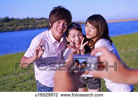 Three people taking pictures and gesturing with smile, View Large Photo Image Stock Image - Three people taking pictures and gesturing with smile,. Fotosearch
