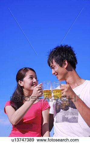 Young couple holding beers and looking at each other with smile, View Large Photo Image Stock Photo - Young couple holding beers and looking at each other with smile,. Fotosearch