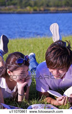Young couple lying on the lawn and reading books with smile, View Large Photo Image Stock Image - Young couple lying on the lawn and reading books with smile,. Fotosearch
