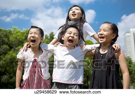 A young lady standing behind three children with arms around and shouting happily View Large Photo Image Stock Photo - A young lady standing behind three children with arms around and shouting happily. Fotosearch