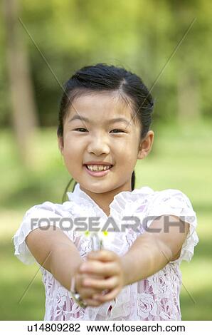 Girl holding flowers and smiling at the camera View Large Photo Image Stock Image - Girl holding flowers and smiling at the camera. Fotosearch
