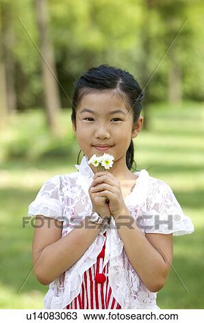Girl smelling flowers and looking at the camera with smile View Large Photo Image Stock Image - Girl smelling flowers and looking at the camera with smile. Fotosearch