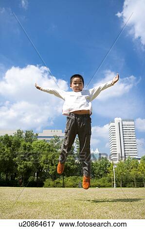 Stock Photo - Little boy jumping in mid-air with arms outstretched and looking down. Fotosearch