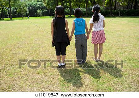 Three children holding hands together and standing in a row View Large Photo Image Stock Photo - Three children holding hands together and standing in a row. Fotosearch