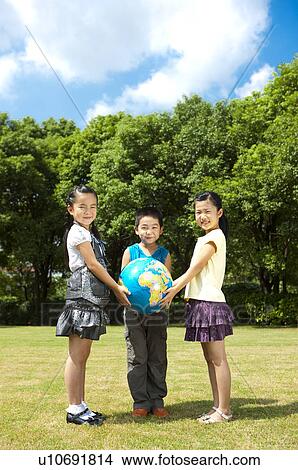 Picture - Three children holding the globe together and looking at the camera with smile. Fotosearch