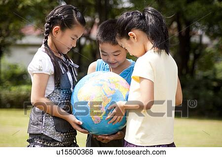 Stock Photo - Three children holding the globe together and looking down. Fotosearch