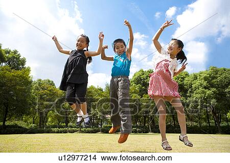 Picture - Three children jumping in mid-air with arms outstretched and smiling. Fotosearch
