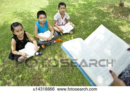 Three children sitting on the lawn, reading together View Large Photo Image Stock Photograph - Three children sitting on the lawn, reading together. Fotosearch
