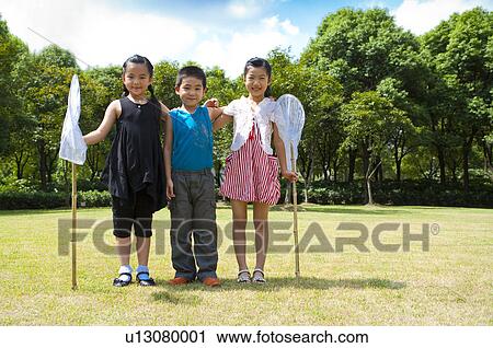 Three children standing in a row and holding butterfly nets with smile View Large Photo Image Stock Image - Three children standing in a row and holding butterfly nets with smile. Fotosearch