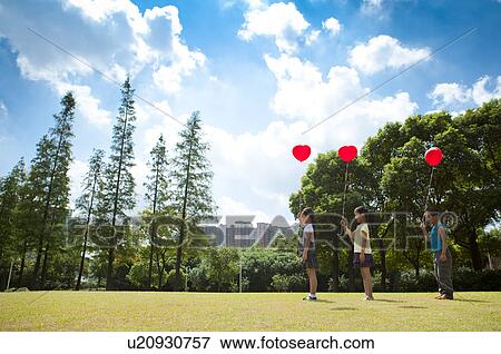 Three children standing in a row and holding balloon together View Large Photo Image Stock Photo - Three children standing in a row and holding balloon together. Fotosearch