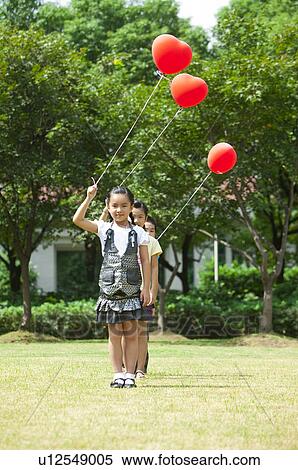 Three children standing in a row and holding balloon together View Large Photo Image Stock Photography - Three children standing in a row and holding balloon together. Fotosearch