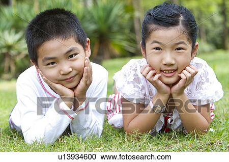 Two children lying on the lawn with head in hands and looking at the camera, Child, View Large Photo Image Stock Image - Two children lying on the lawn with head in hands and looking at the camera, Child,. Fotosearch
