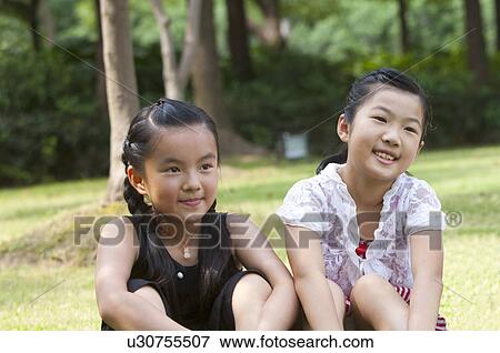 Two girls sitting together and looking away with smile View Large Photo Image Stock Photo - Two girls sitting together and looking away with smile. Fotosearch