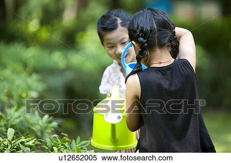 Two girls watering plants in the garden View Large Photo Image Stock Photography - Two girls watering plants in the garden. Fotosearch