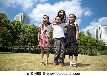 Stock Image - Young woman and children standing together and shouting with mouth open. Fotosearch