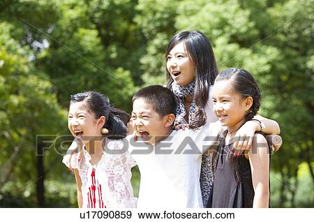 Stock Photo - Young woman and children standing with arms around and shouting with mouth open. Fotosearch