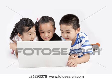 Stock Photo - Child, Children lying on front and looking at the laptop together. Fotosearch