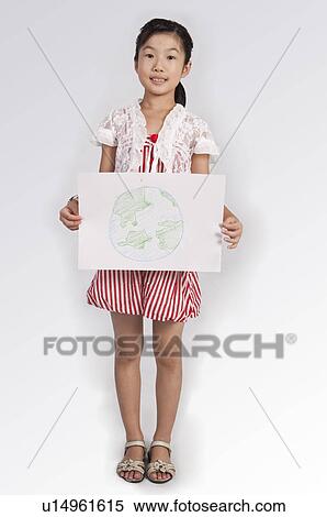 Stock Photography - Child, Girl standing and showing a drawing with smile. Fotosearch