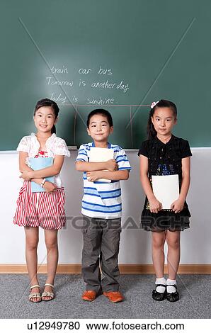 Stock Image - Child, Three children standing in a row and holding book with smile. Fotosearch