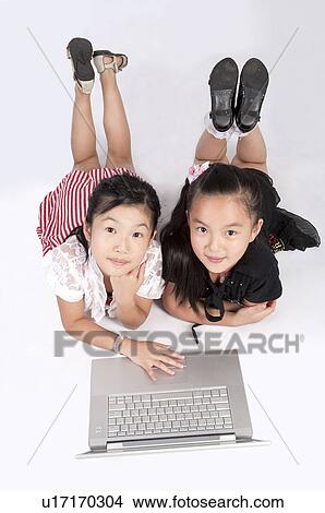 Child, Two girls lying on front with laptop and looking up together View Large Photo Image Picture - Child, Two girls lying on front with laptop and looking up together. Fotosearch