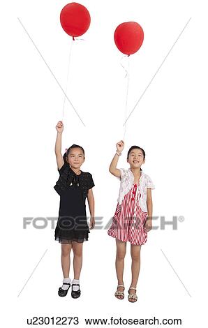 Stock Image - Child, Two girls standing and holding balloon with smile together. Fotosearch