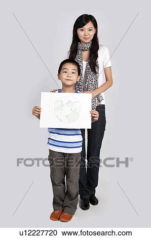 Child, Young teacher and boy standing together and holding a drawing View Large Photo Image Stock Image - Child, Young teacher and boy standing together and holding a drawing. Fotosearch