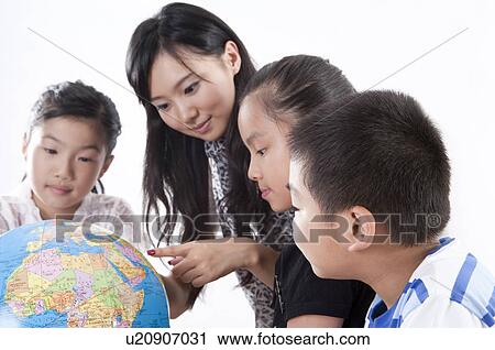 Stock Image - Child, Young teacher and students looking at the globe together. Fotosearch