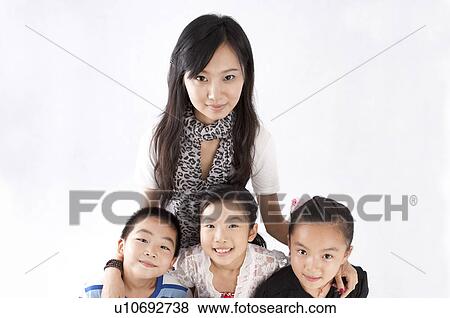 Stock Photo - Child, Young teacher standing with children and looking at the camera together. Fotosearch