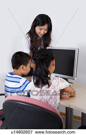 Child, Young teacher teaching and looking at the computer with children View Large Photo Image Stock Photo - Child, Young teacher teaching and looking at the computer with children. Fotosearch