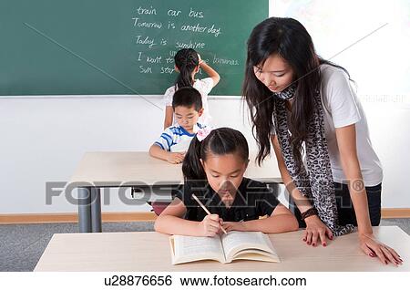 Stock Photograph - Child, Young teacher teaching children in the classroom. Fotosearch