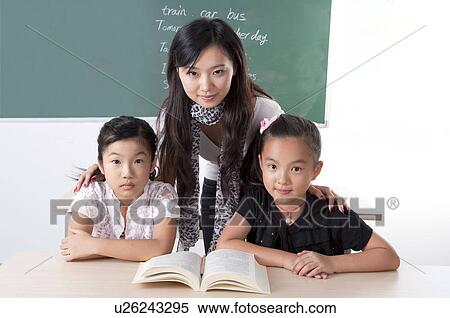 Stock Photography - Child, Young teacher teaching children and looking at the camera together. Fotosearch