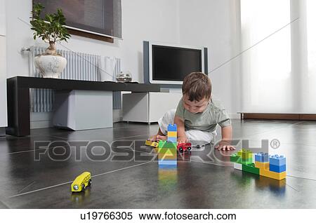 Stock Photography - Baby boy playing with toys in living room. Fotosearch