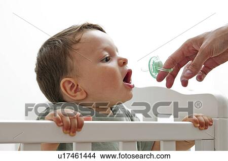 Picture - Baby boy with female hand giving pacifier. Fotosearch