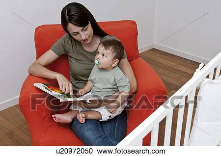 Young woman and baby boy sitting on arm chair reading a book View Large Photo Image Stock Image - Young woman and baby boy sitting on arm chair reading a book. Fotosearch