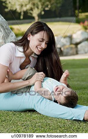 Stock Photo - Young woman playing in garden with baby boy. Fotosearch