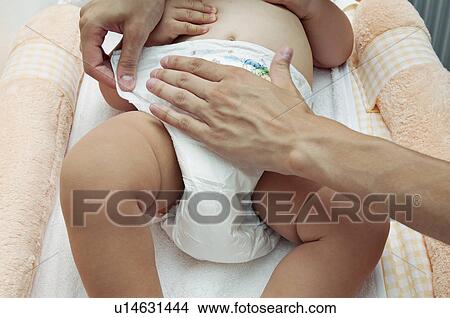 Picture - Young woman's hands changing baby's diaper. Fotosearch