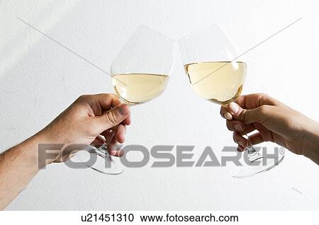 Stock Image - Closeup male and female hands holding wine glasses and toasting. Fotosearch