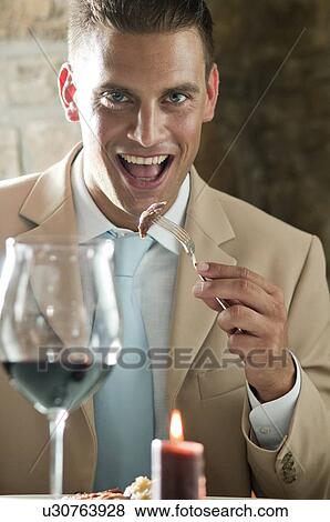 Young man eating with glass of wine at a restaurant View Large Photo Image Stock Photo - Young man eating with glass of wine at a restaurant. Fotosearch