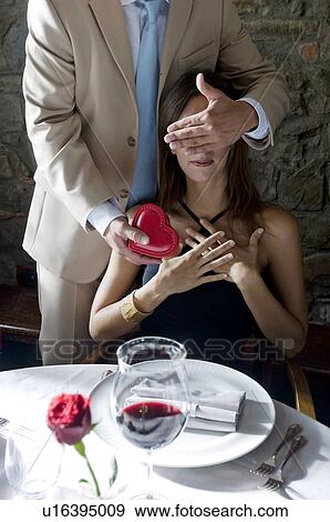Young man giving a present to young woman with hand covering her eyes View Large Photo Image Stock Photo - Young man giving a present to young woman with hand covering her eyes. Fotosearch