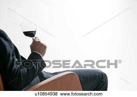 Stock Photo - Young man in business suit sitting with glass of red wine. Fotosearch