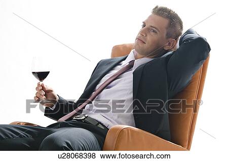 Young man in business suit sitting with glass of red wine View Large Photo Image Stock Photo - Young man in business suit sitting with glass of red wine. Fotosearch