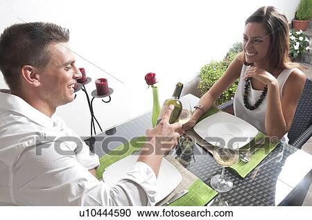 Young man pouring wine for young woman at restaurant table View Large Photo Image Stock Image - Young man pouring wine for young woman at restaurant table. Fotosearch