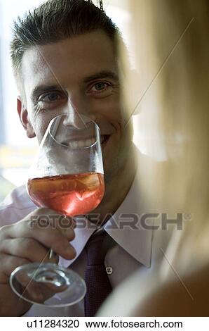 Young man sitting with a glass of orange wine and young woman View Large Photo Image Stock Image - Young man sitting with a glass of orange wine and young woman. Fotosearch